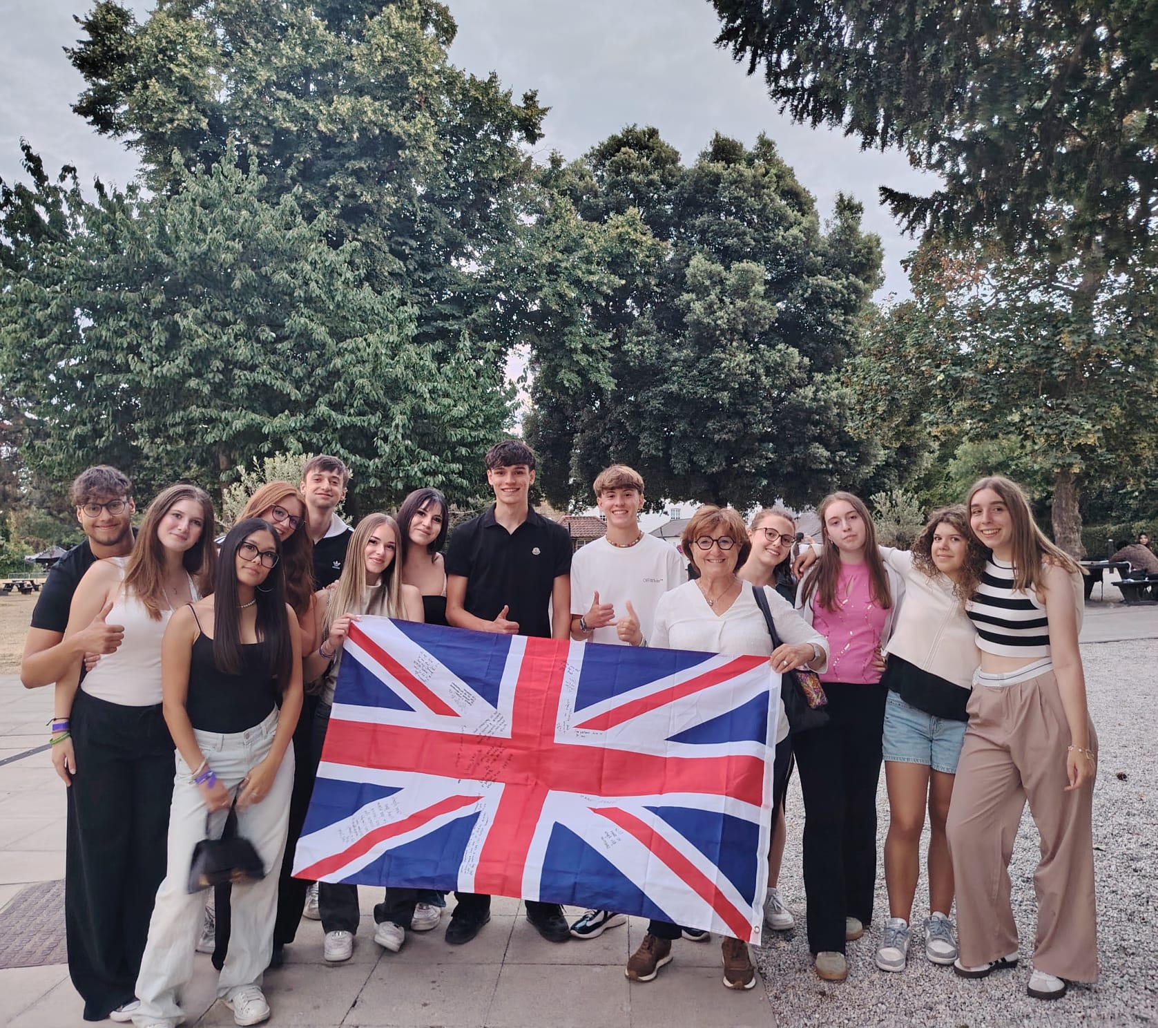 Gruppo di studenti e accompagnatrice in Regno Unito con una bandiera britannica firmata.
