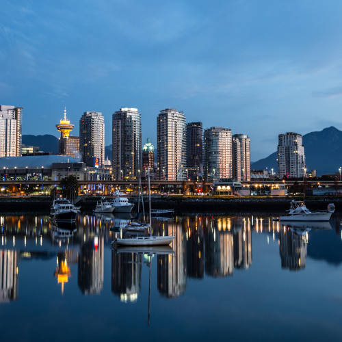 Downtown Vancouver reflecting off the glass-like surface of False Creek early in the morning. The North Shore Mountains are in the background.